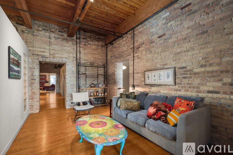A living room with a couch, a chair, and a table with a colorful tablecloth.