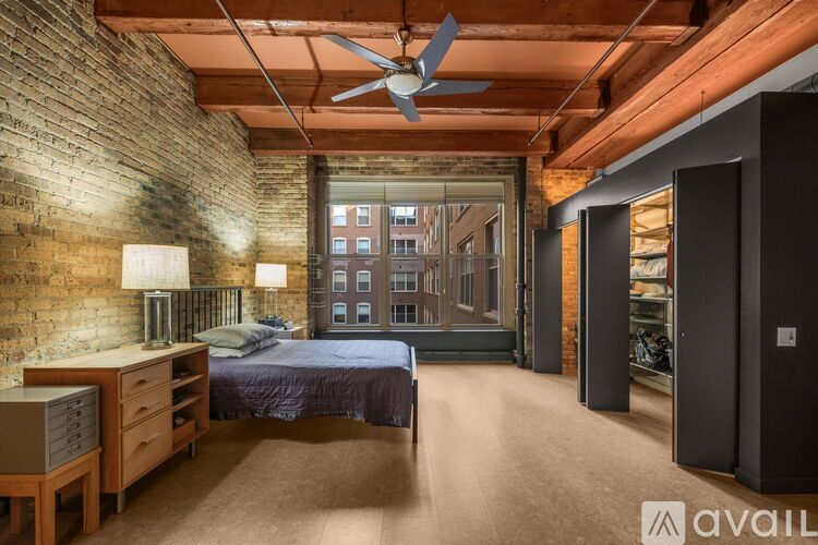 A bedroom with a brick wall and a bed with a blue comforter.