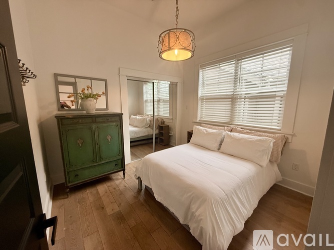 A bedroom with a white bed and a green cabinet.