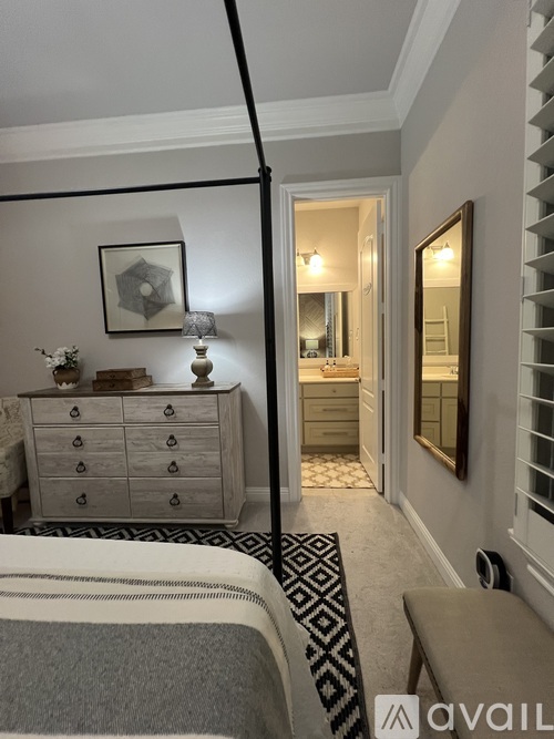 A bedroom with a bed, dresser, mirror, and a rug.
