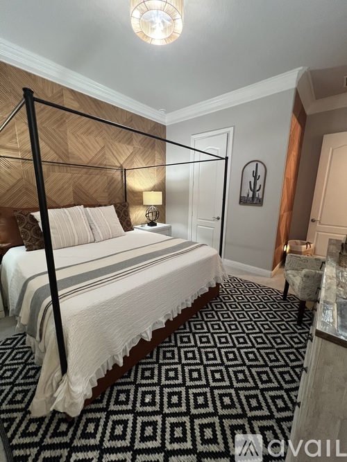 A bedroom with a four poster bed and a patterned carpet.