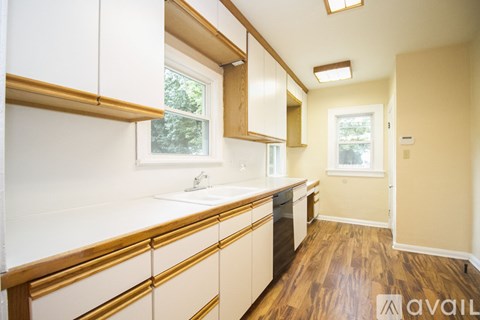 A kitchen with white cabinets and a wooden floor.