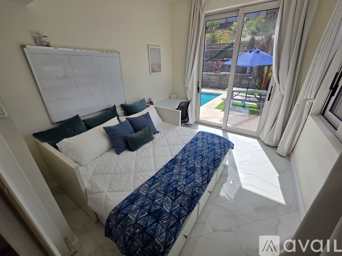 A bedroom with a large bed and a view of a pool outside.