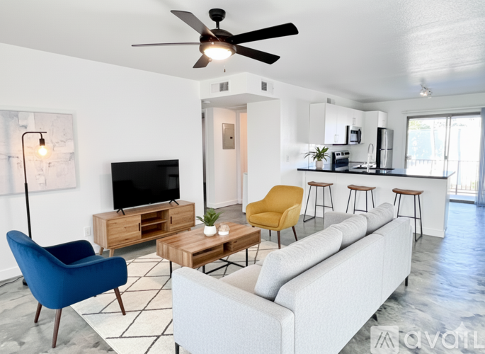 A living room with a white couch, a blue chair, and a television.