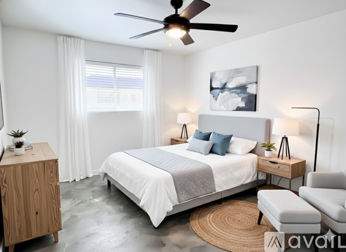 A bedroom with a large bed, a ceiling fan, and a rug on the floor.