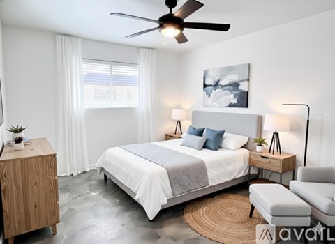 A bedroom with a large bed, a ceiling fan, and a rug on the floor.