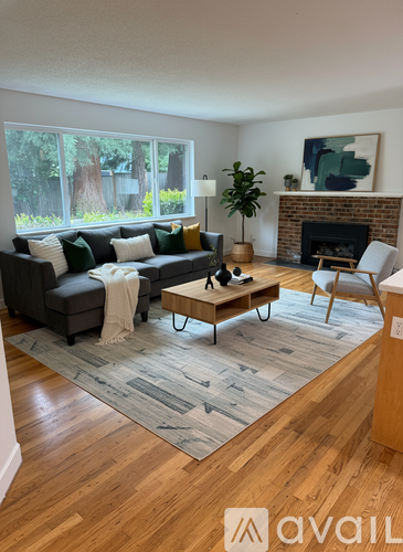 A living room with a grey couch, a coffee table, a fireplace, and a painting on the wall.