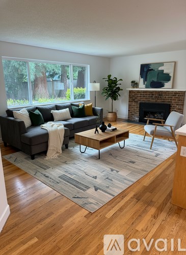 A living room with a grey couch, a coffee table, a fireplace, and a painting on the wall.