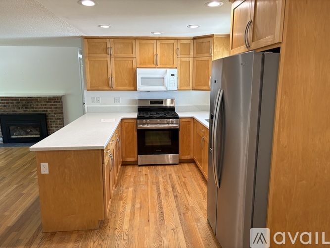 A kitchen with wooden cabinets and a stainless steel refrigerator.