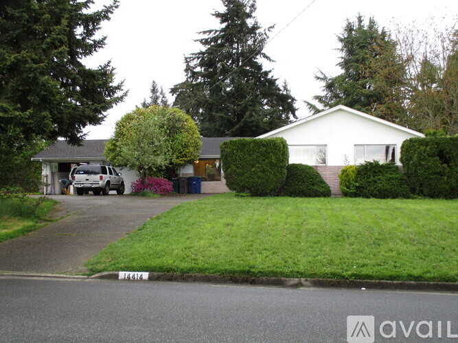 A house with a white exterior and a green lawn in front.