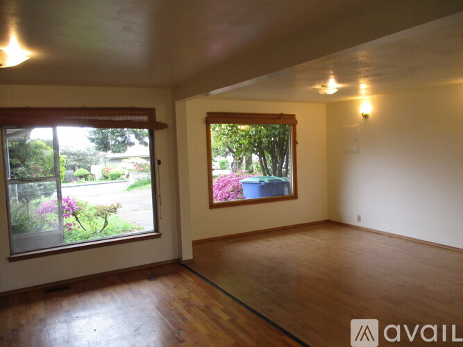 A room with wooden floors and two windows showing an outdoor view.