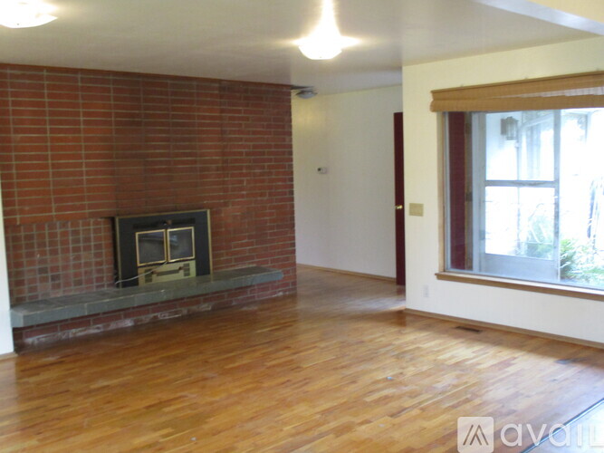 A room with a brick fireplace and wooden floors.