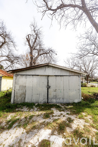A small white shed sits in a grassy field.