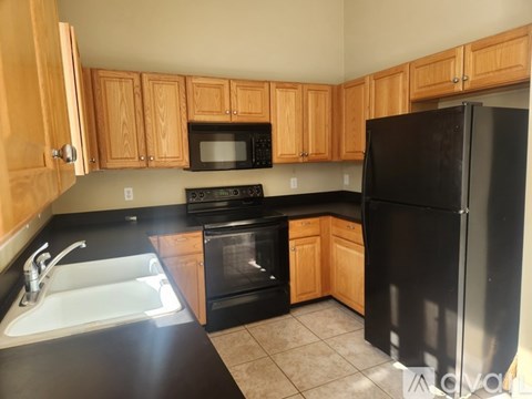A kitchen with black appliances and wooden cabinets.
