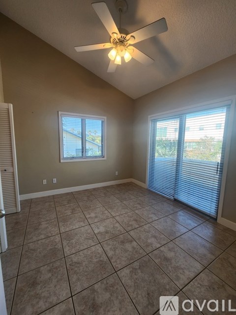 A room with a ceiling fan and tiled floor.