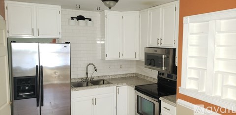 A kitchen with white cabinets and a silver refrigerator.