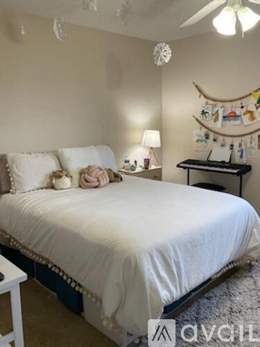 A bedroom with a white bed and a desk with a lamp.