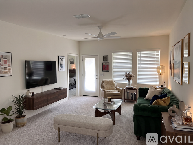 A living room with a television, a couch, a chair, a coffee table, and a potted plant.