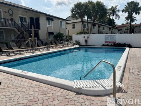 A pool surrounded by a white fence and chairs.
