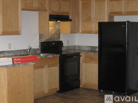 A kitchen with wooden cabinets and a black fridge.