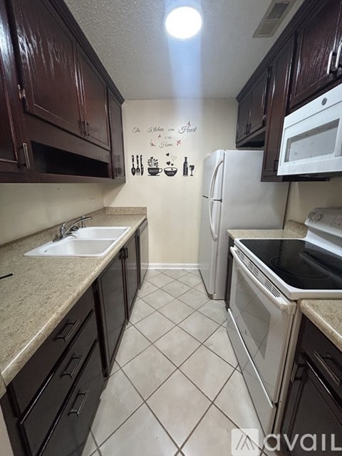 A kitchen with brown cabinets and white appliances.
