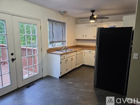 A kitchen with white cabinets and a black refrigerator.