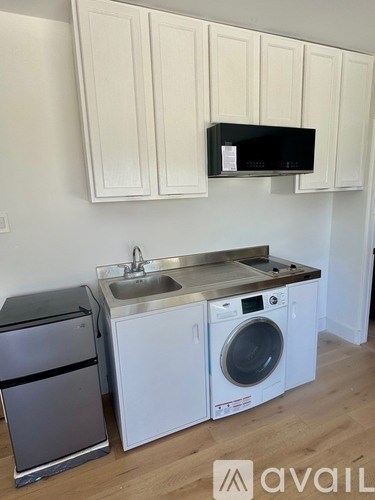 A kitchen with a black microwave above a stainless steel sink.