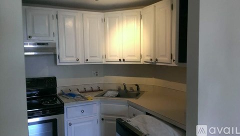 A kitchen with white cabinets and a stove top oven.