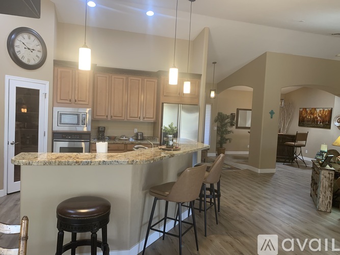 A kitchen with a marble countertop and bar stools.