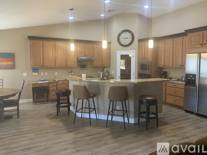 A kitchen with wooden cabinets and a large island with four stools.
