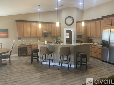 A kitchen with wooden cabinets and a large island with four stools.
