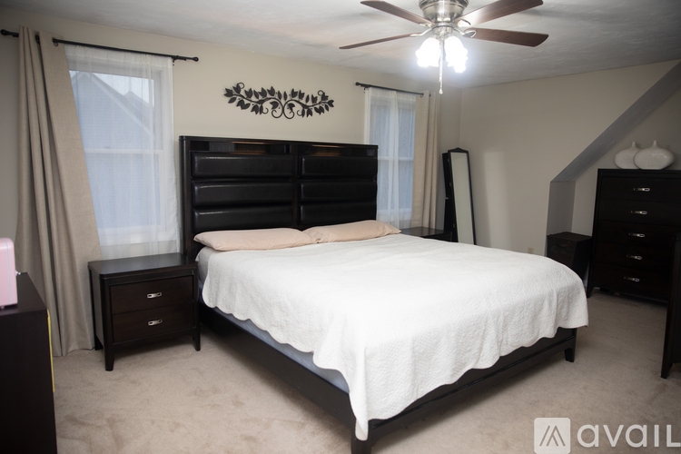 A bedroom with a large bed and a ceiling fan.