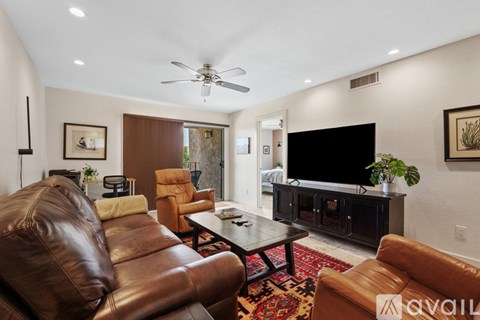 A living room with a brown leather couch and a flat screen TV.