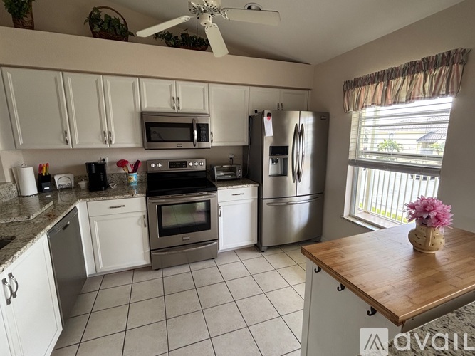 A kitchen with white cabinets and a wooden island.
