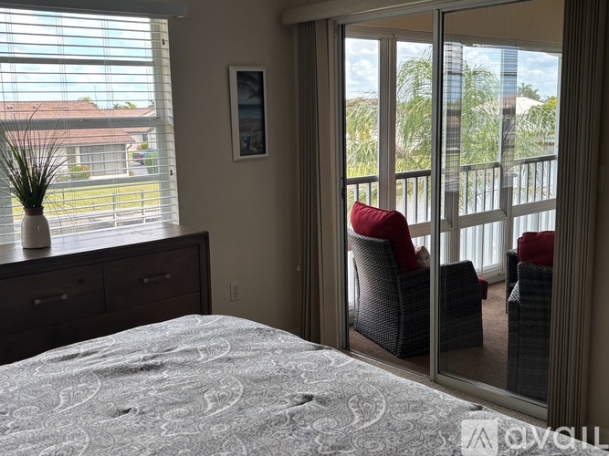 A bedroom with a bed, chair, and a window overlooking a balcony.
