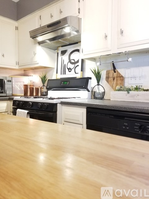 A kitchen with a black stove top oven and wooden floors.