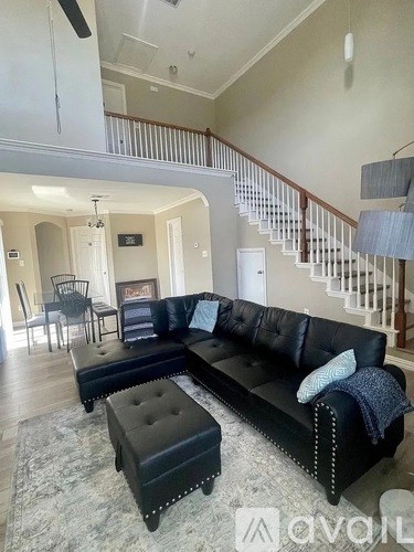 A living room with a black leather couch and ottoman.