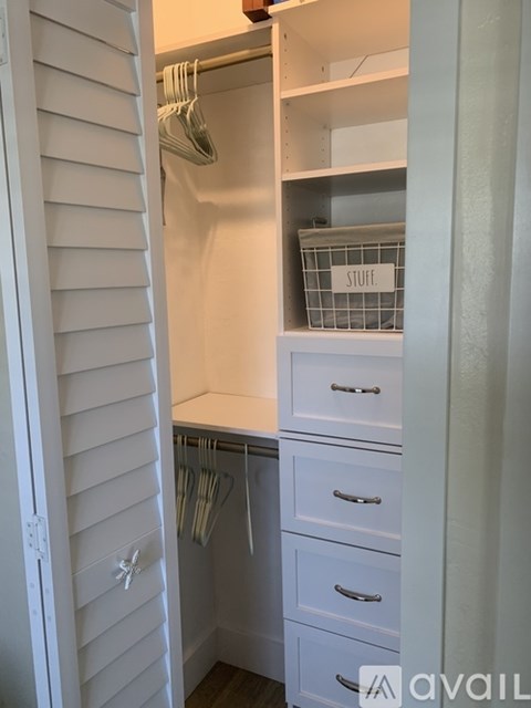A small closet with a basket labeled "stuff" on the shelf.