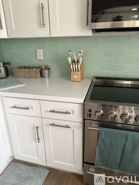 A kitchen with white cabinets and a green tile backsplash.