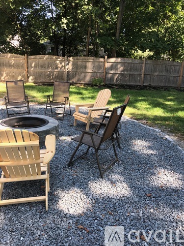 A patio with a fire pit and chairs.