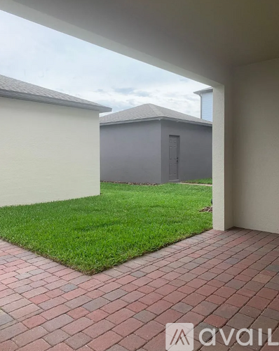 A patio area with a brick floor and a grassy area in the background.