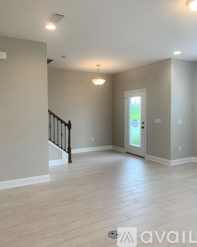 A spacious room with a staircase and a door leading to a balcony.