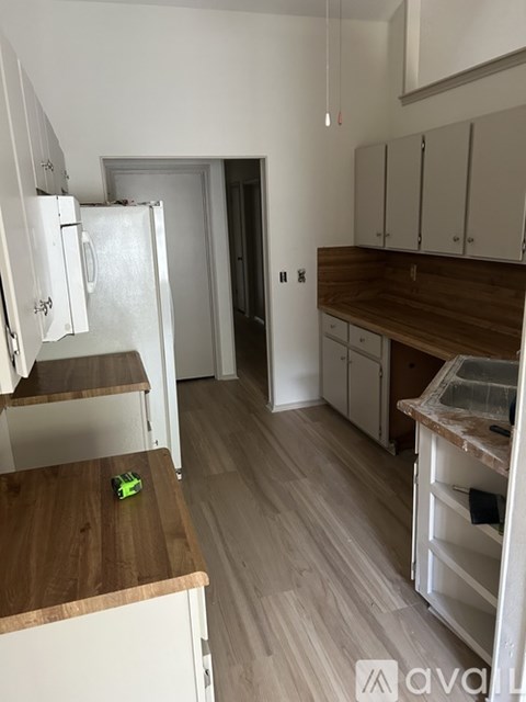 A kitchen with white cabinets and a wooden counter top.