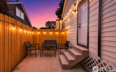 A patio with a table and chairs is lit by string lights.