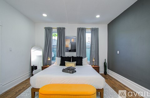 A bedroom with a large bed and a window with curtains.