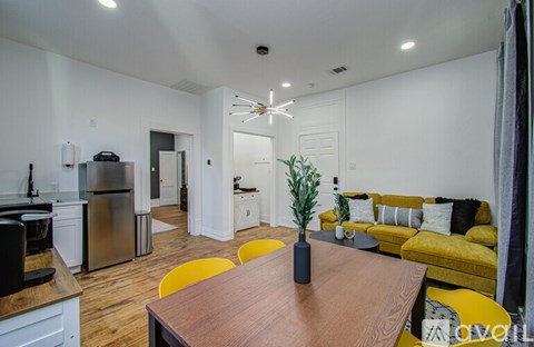 A modern kitchen with a wooden table and yellow chairs.