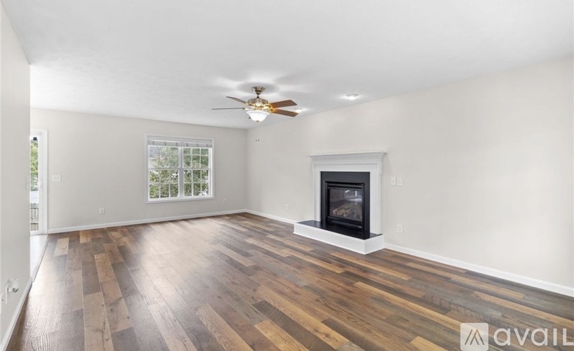 A spacious room with a fireplace and wooden flooring.