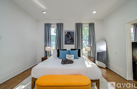A bedroom with a large bed and a window with curtains.