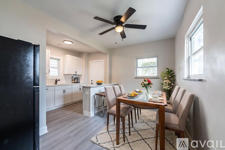 A dining room with a table set for four and a refrigerator to the left.