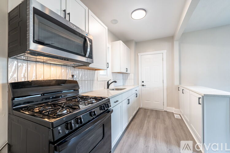 A modern kitchen with a black stove and white cabinets.